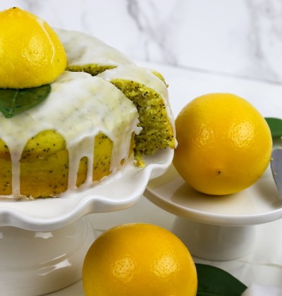 a cake stand with vegan lemon drizzle cake and lemons